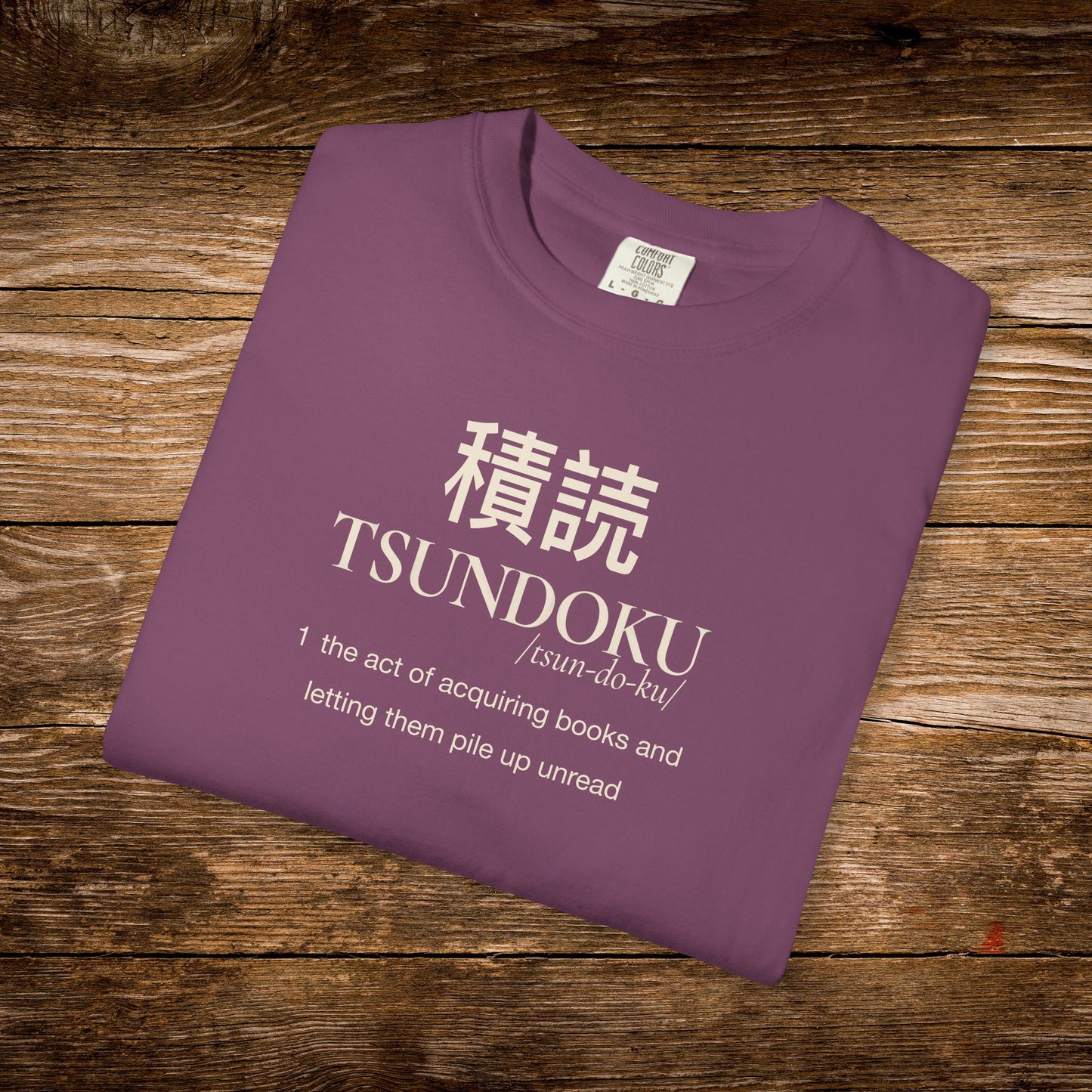 Folded berry Comfort Colors T-shirt featuring the Tsundoku dictionary definition design.