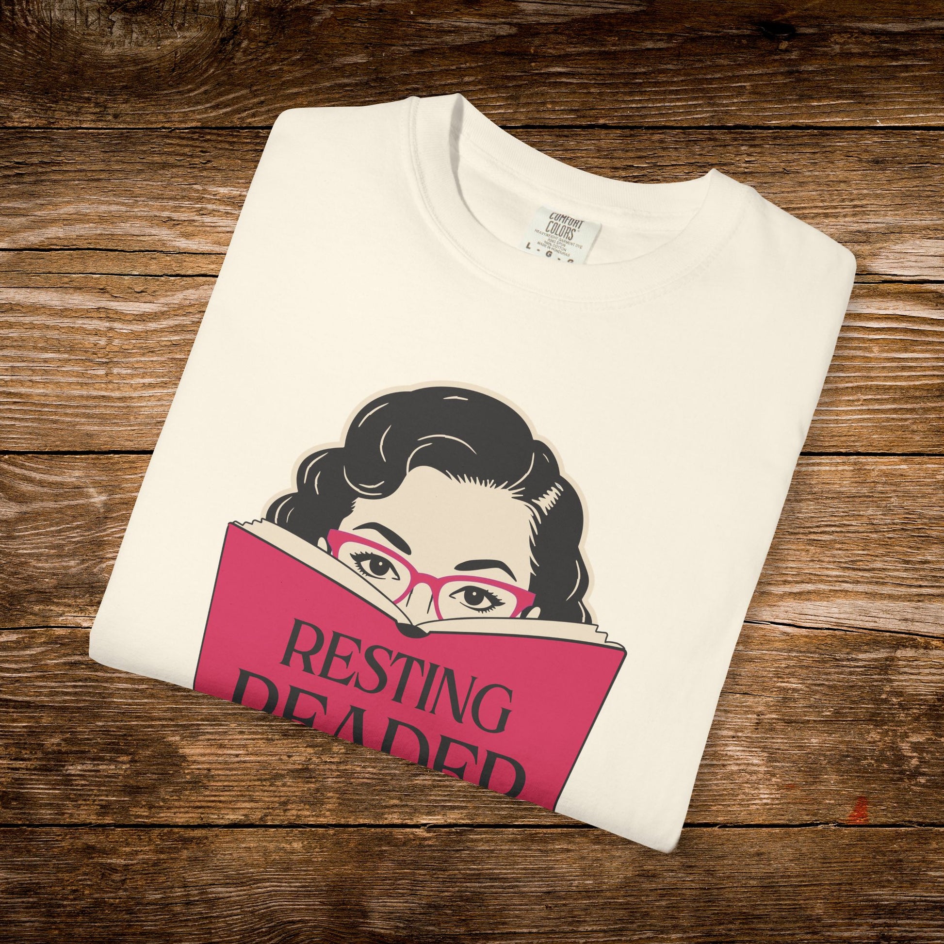 Folded ivory Resting Reader Face graphic t-shirt with vintage reader design.