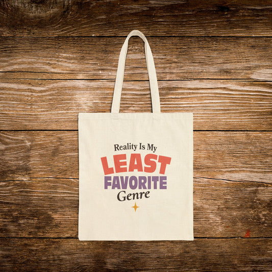 A cream canvas tote bag with the printed phrase 'Reality Is My LEAST FAVORITE Genre' in red, purple, and black lettering, displayed flat against a rustic brown wooden plank background.