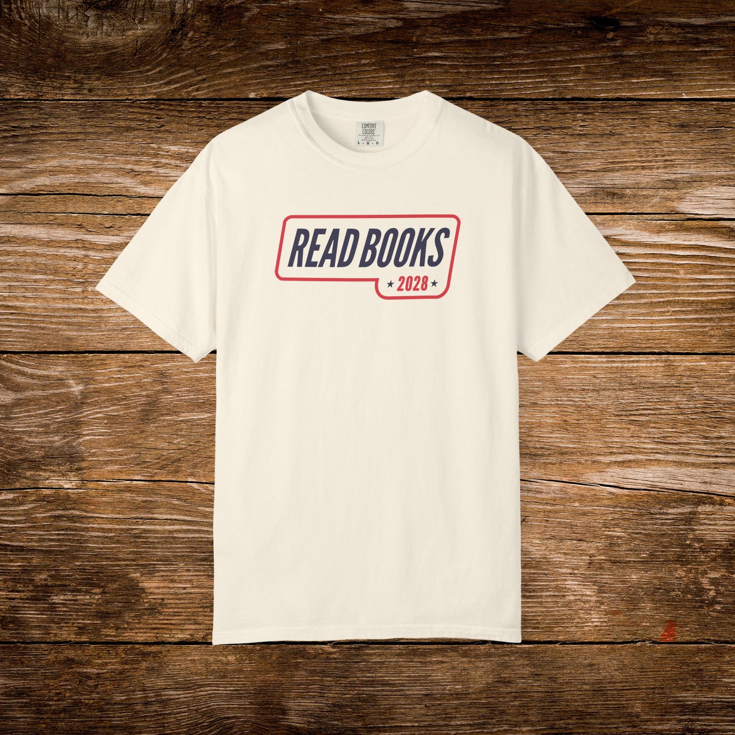 5. Flat Lay
    Ivory Read Books 2028 graphic t-shirt on a wooden background.