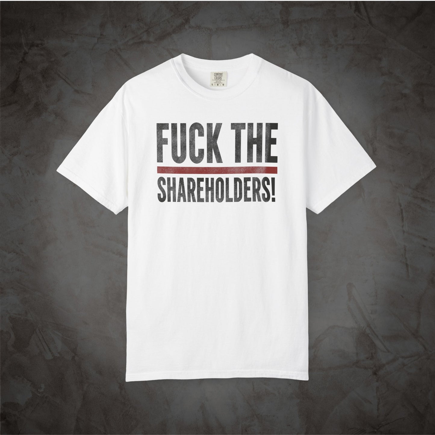 A white short-sleeve crewneck t-shirt with the text 'FUCK THE SHAREHOLDERS!' printed in black across the chest, separated by a thin red horizontal line, displayed against a dark textured gray background.