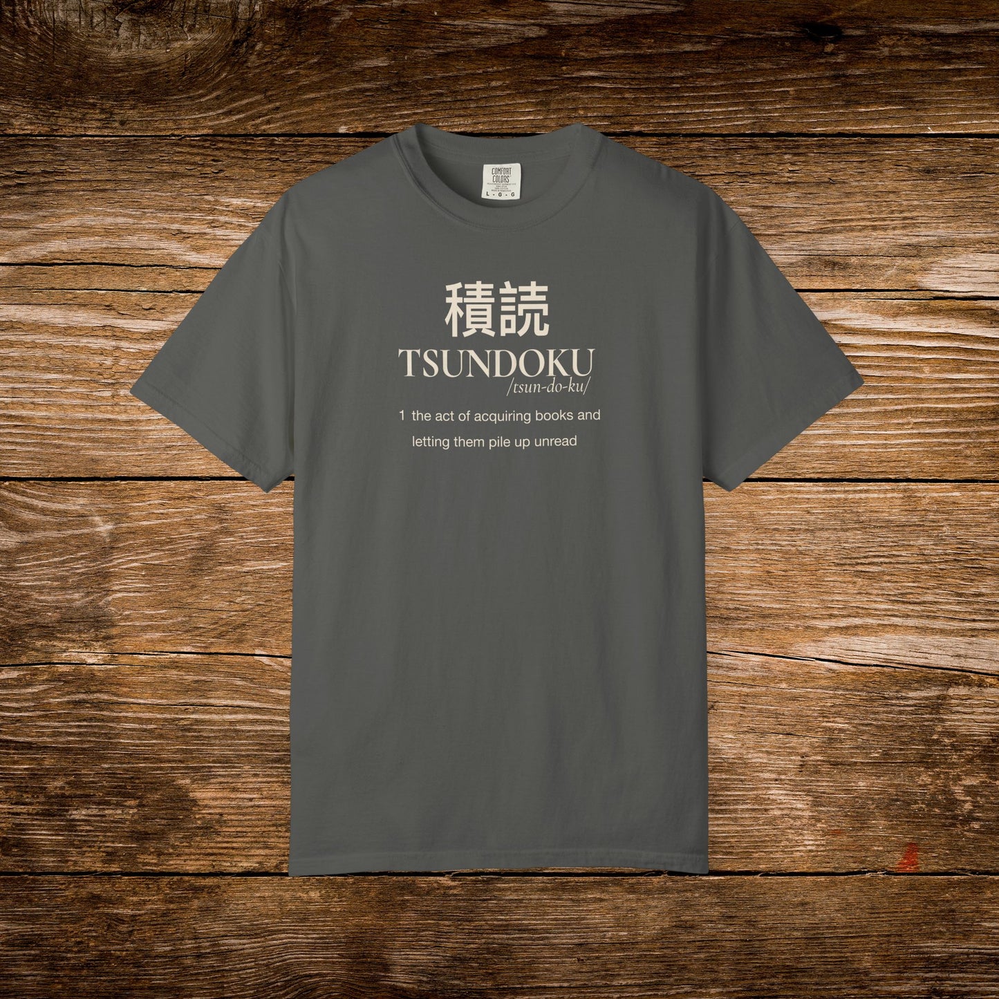 Tsundoku dictionary definition printed on a pepper Comfort Colors T-shirt with minimalist vintage typography.