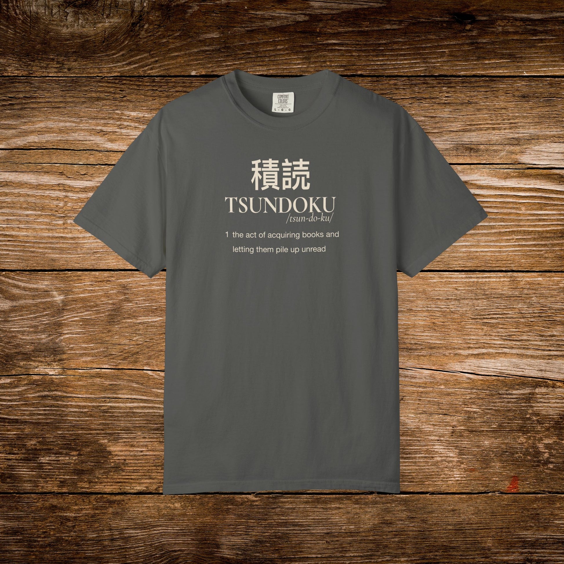 Tsundoku dictionary definition printed on a pepper Comfort Colors T-shirt with minimalist vintage typography.