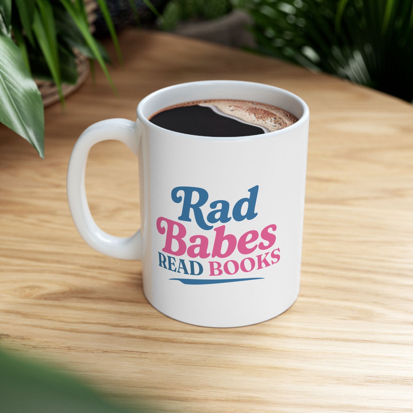 2. Lifestyle Mockup
    Rad Babes Read Books ceramic mug filled with coffee on a wooden table.