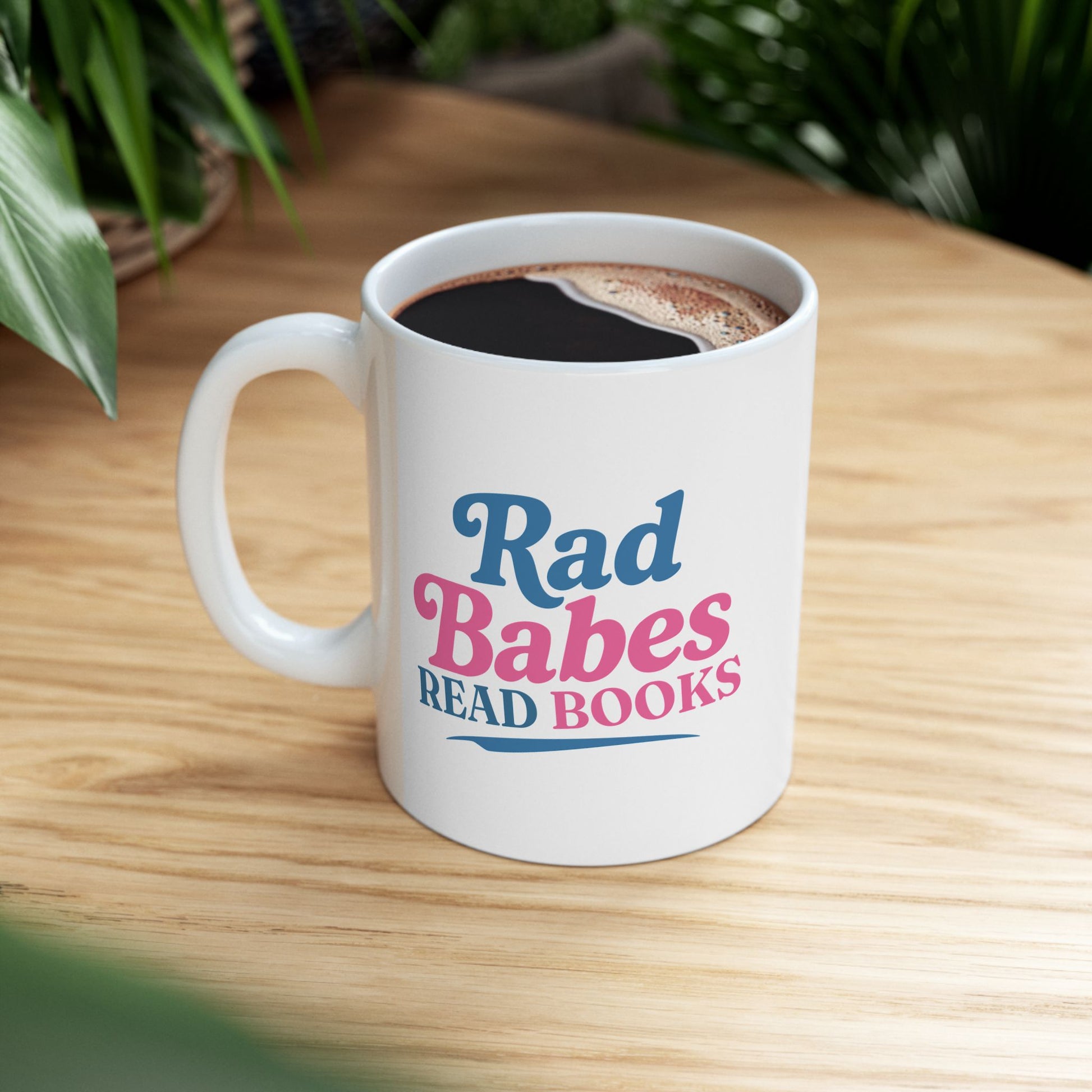 2. Lifestyle Mockup
    Rad Babes Read Books ceramic mug filled with coffee on a wooden table.