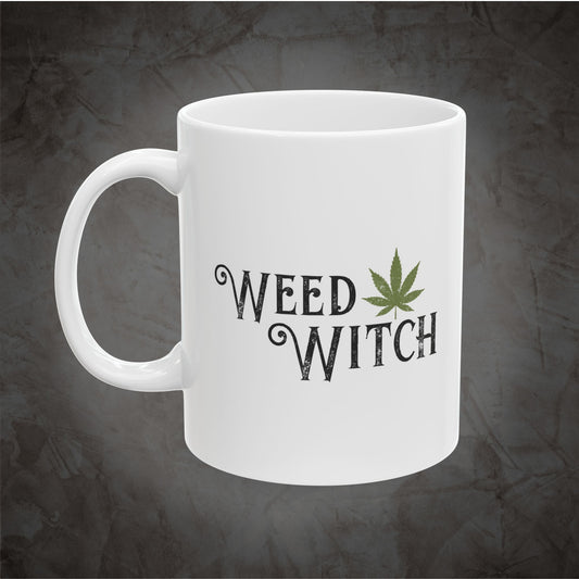 A white ceramic mug with the words 'WEED WITCH' printed in a dark gothic font, accompanied by a green cannabis leaf graphic, set against a dark textured gray background.