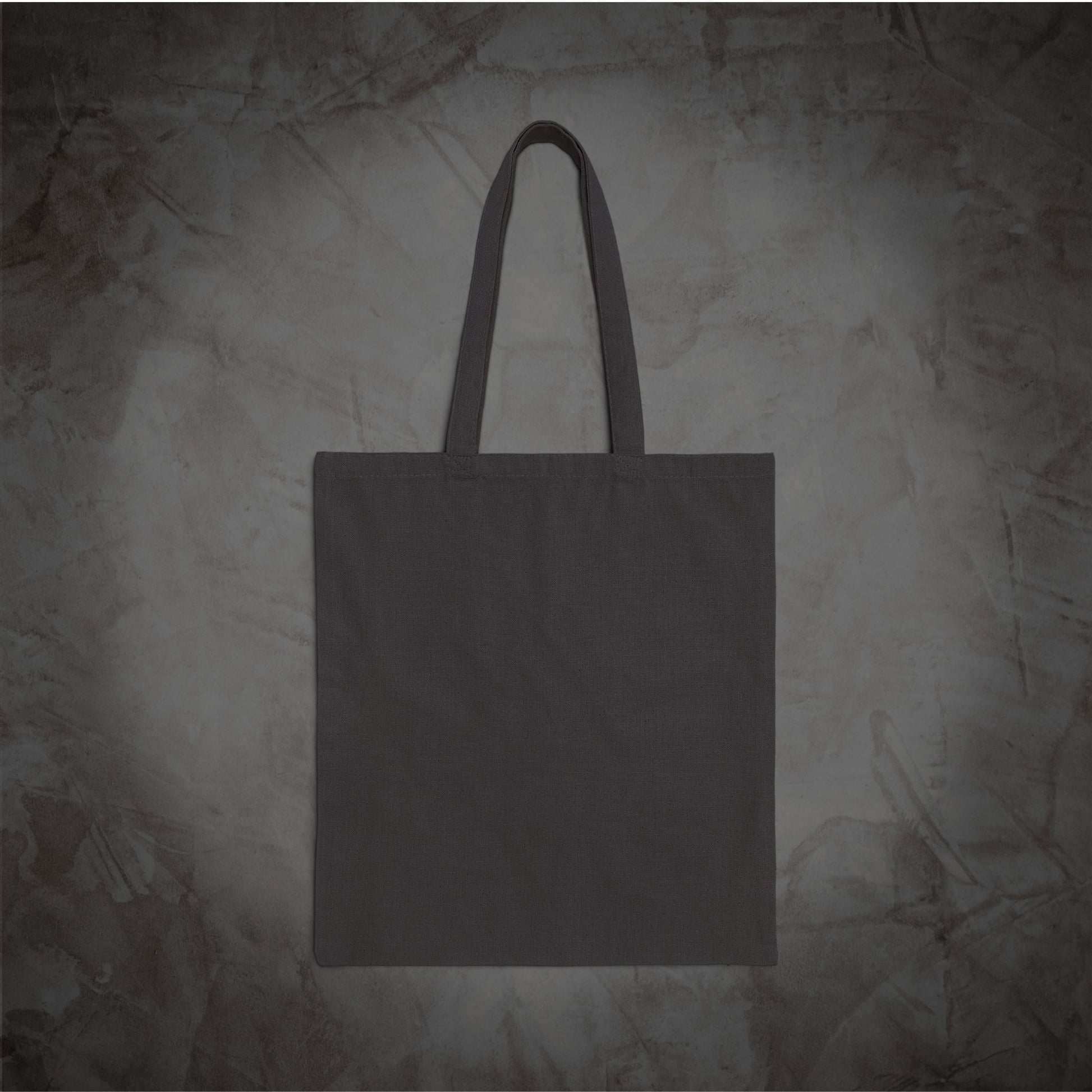 A plain dark gray canvas tote bag with two handles, centered against a textured gray background.