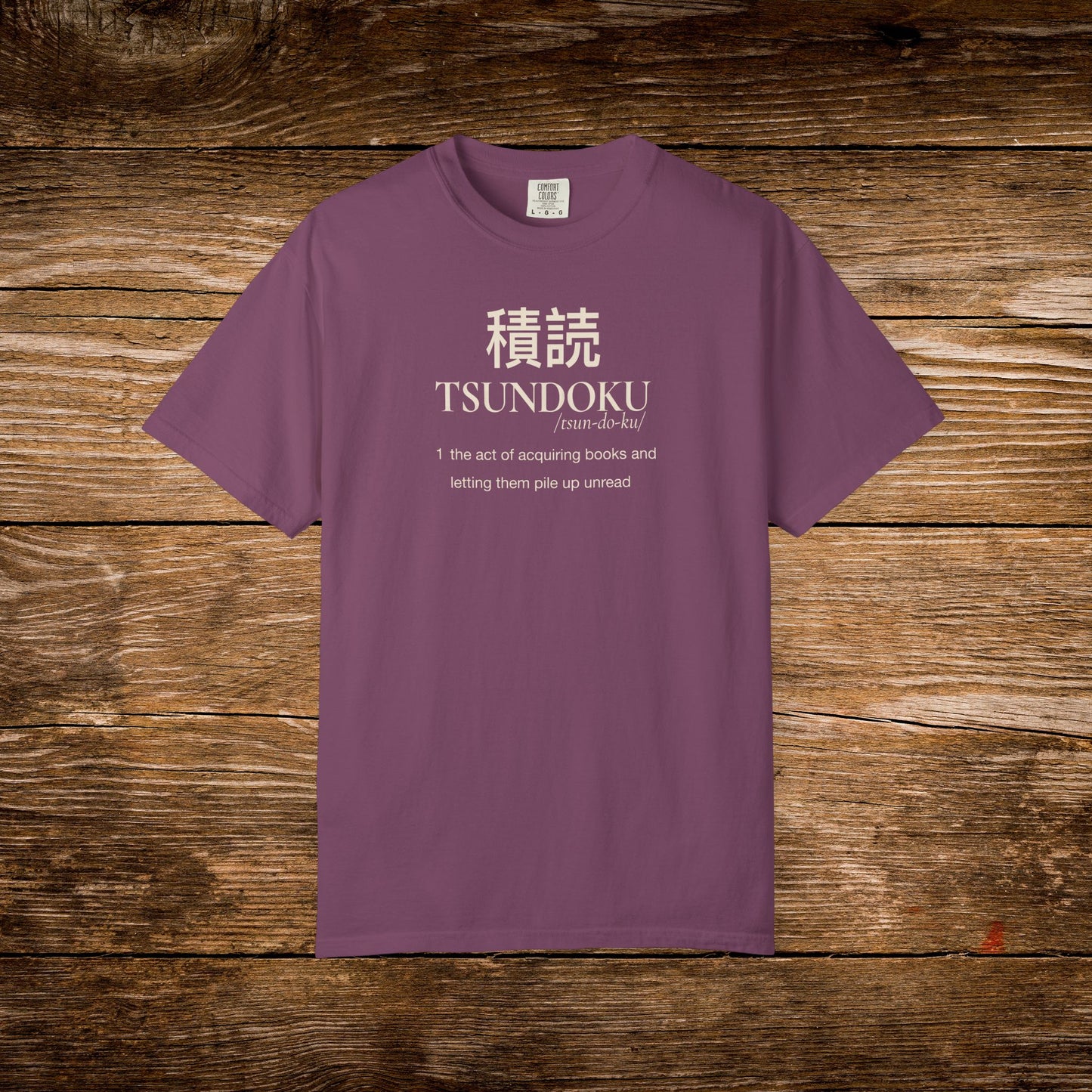 Tsundoku dictionary definition printed on a berry Comfort Colors T-shirt with minimalist vintage typography.