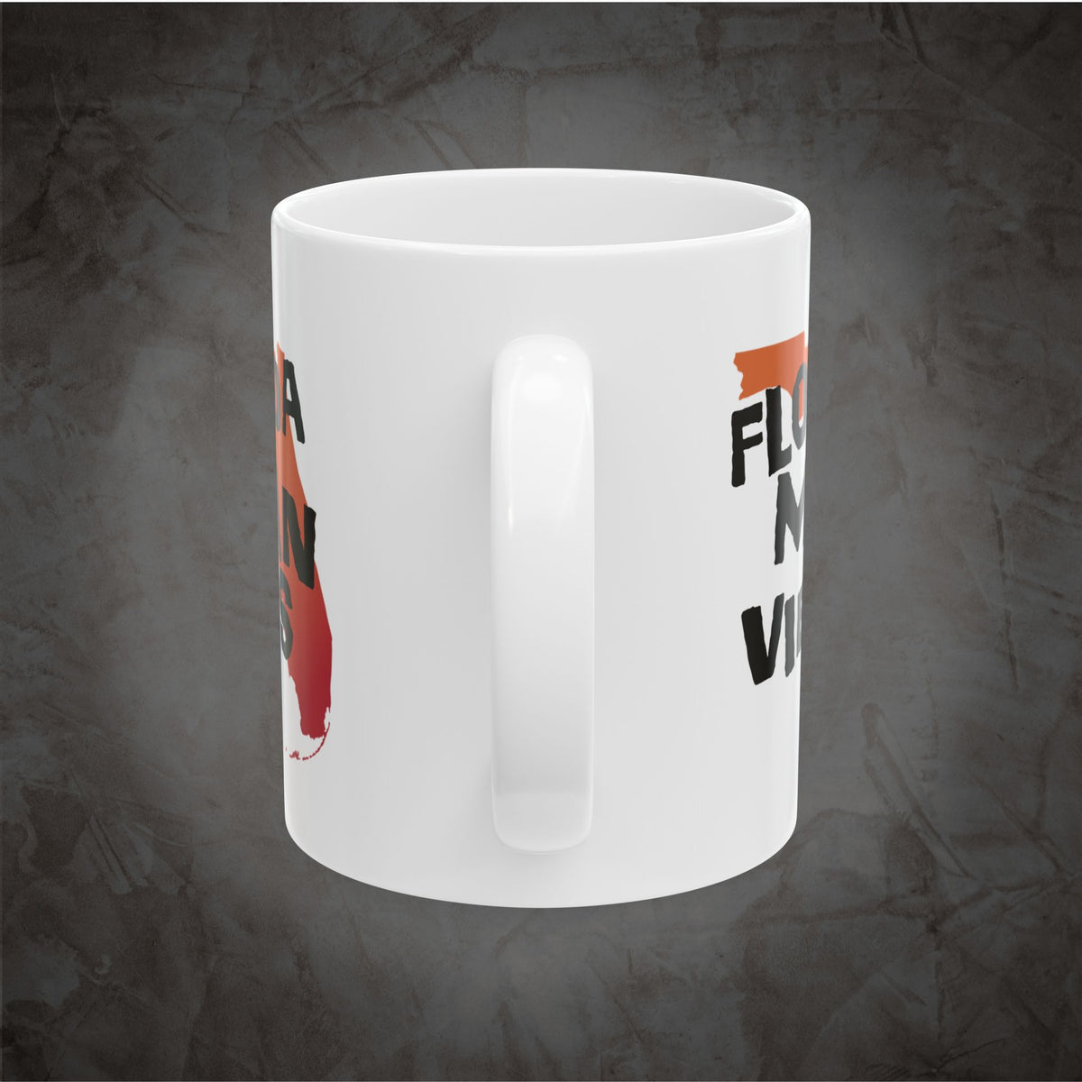 A white ceramic coffee mug with a handle, featuring partial black and orange text and a red-orange graphic on a textured dark gray background.