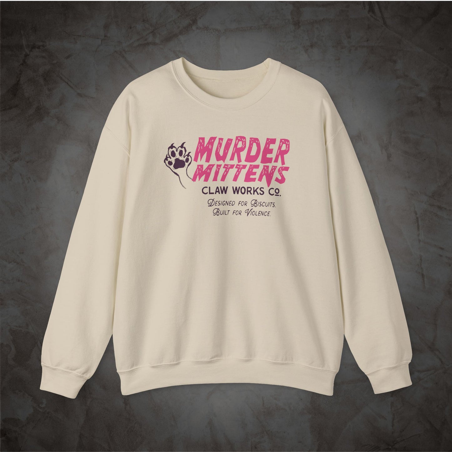 An off-white crewneck sweatshirt with a pink and black graphic on the chest reading 'MURDER MITTENS CLAW WORKS CO.' and 'Beware of Predators.