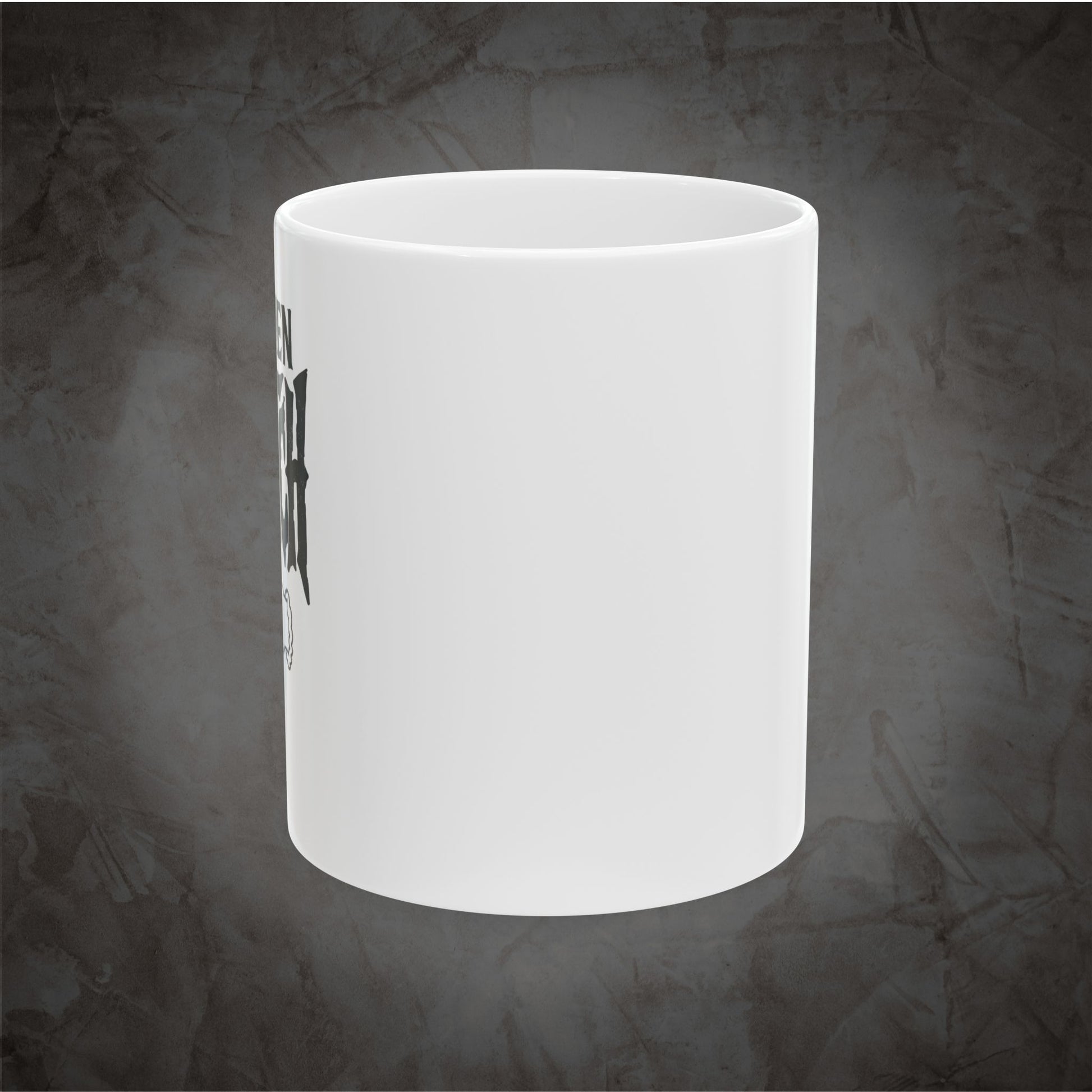 A white ceramic mug with a black graphic print on the side, shown against a textured dark gray background.