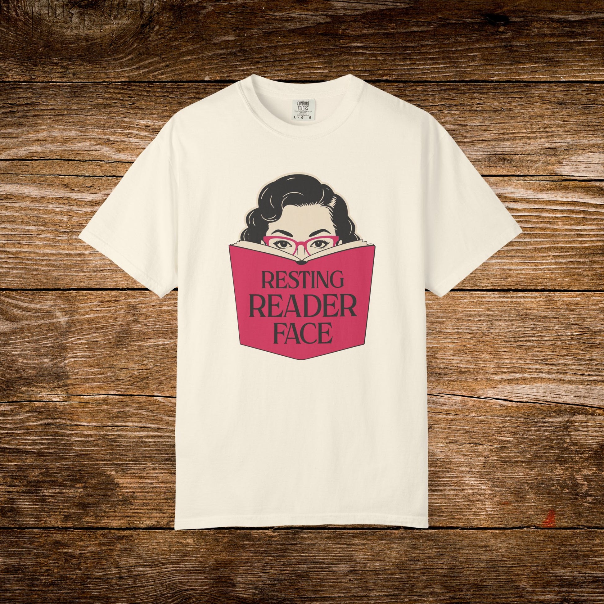 Ivory Resting Reader Face graphic t-shirt shown on a wooden background.