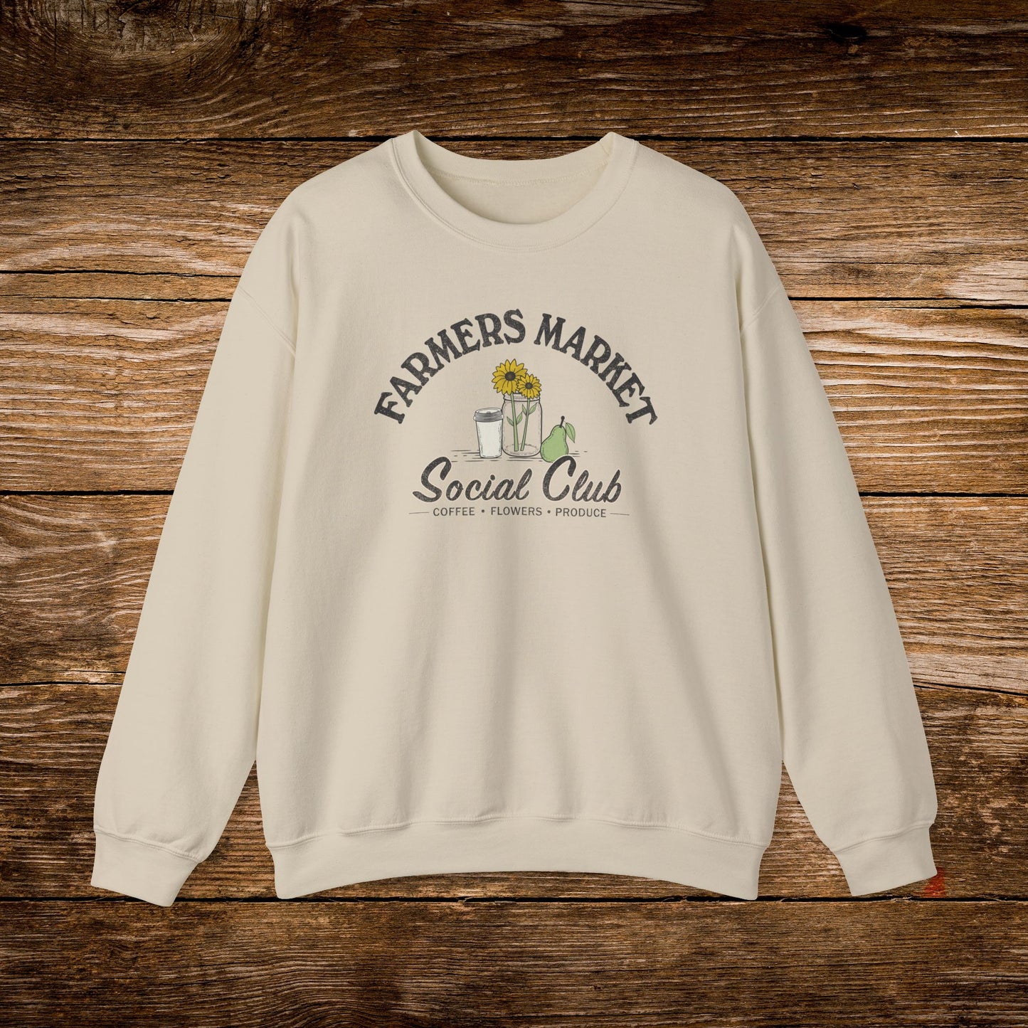 An off-white crewneck sweatshirt with a 'Farmers Market Social Club' graphic printed on the chest, displayed flat on a rustic wooden plank background.