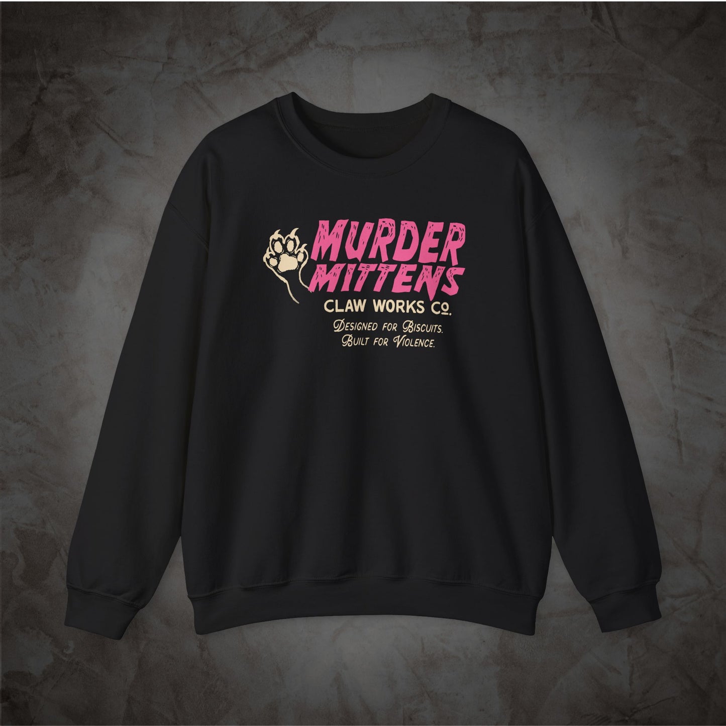 A black crewneck sweatshirt with a graphic on the chest reading 'MURDER MITTENS CLAN WORKS CO' in pink and white, with a fist illustration, displayed on a textured gray background.