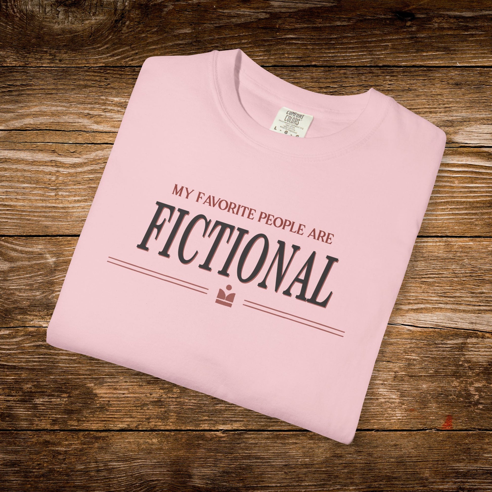 Folded pink t-shirt with text on a wooden surface