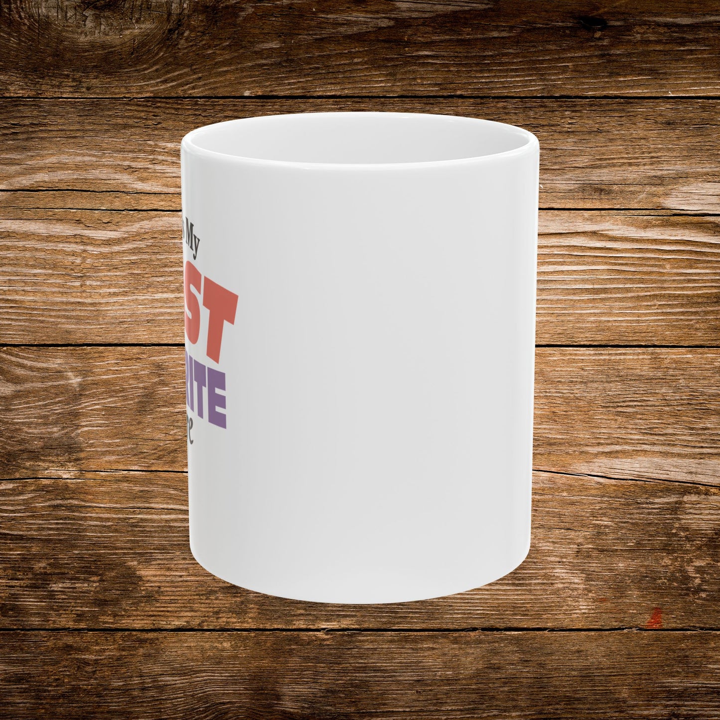 A white ceramic mug with partial red and purple text design, shown against a rustic brown wooden plank background.