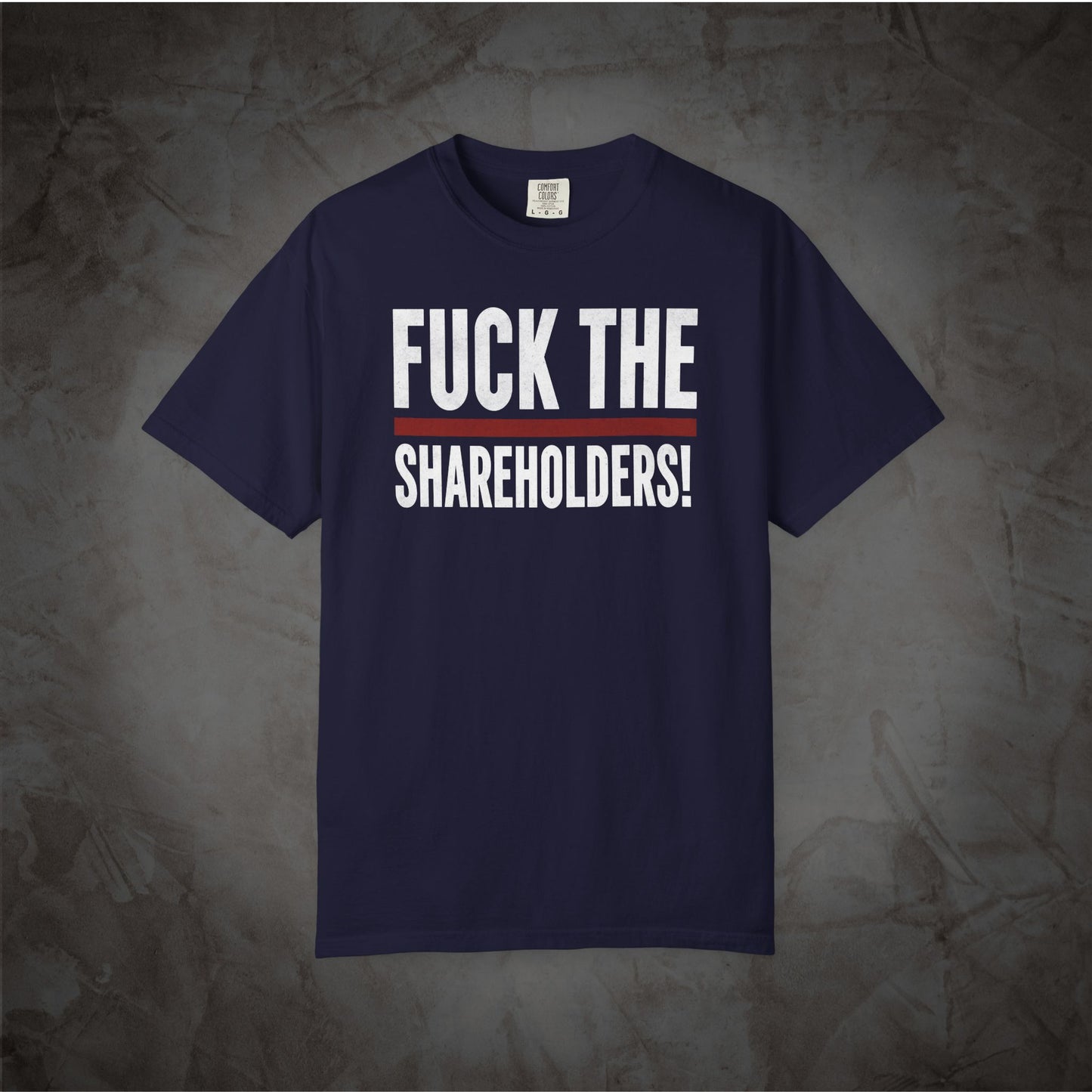 A navy blue short-sleeve t-shirt with the text 'FUCK THE SHAREHOLDERS!' printed in white across the chest, separated by a thin red horizontal line, displayed against a textured gray background.