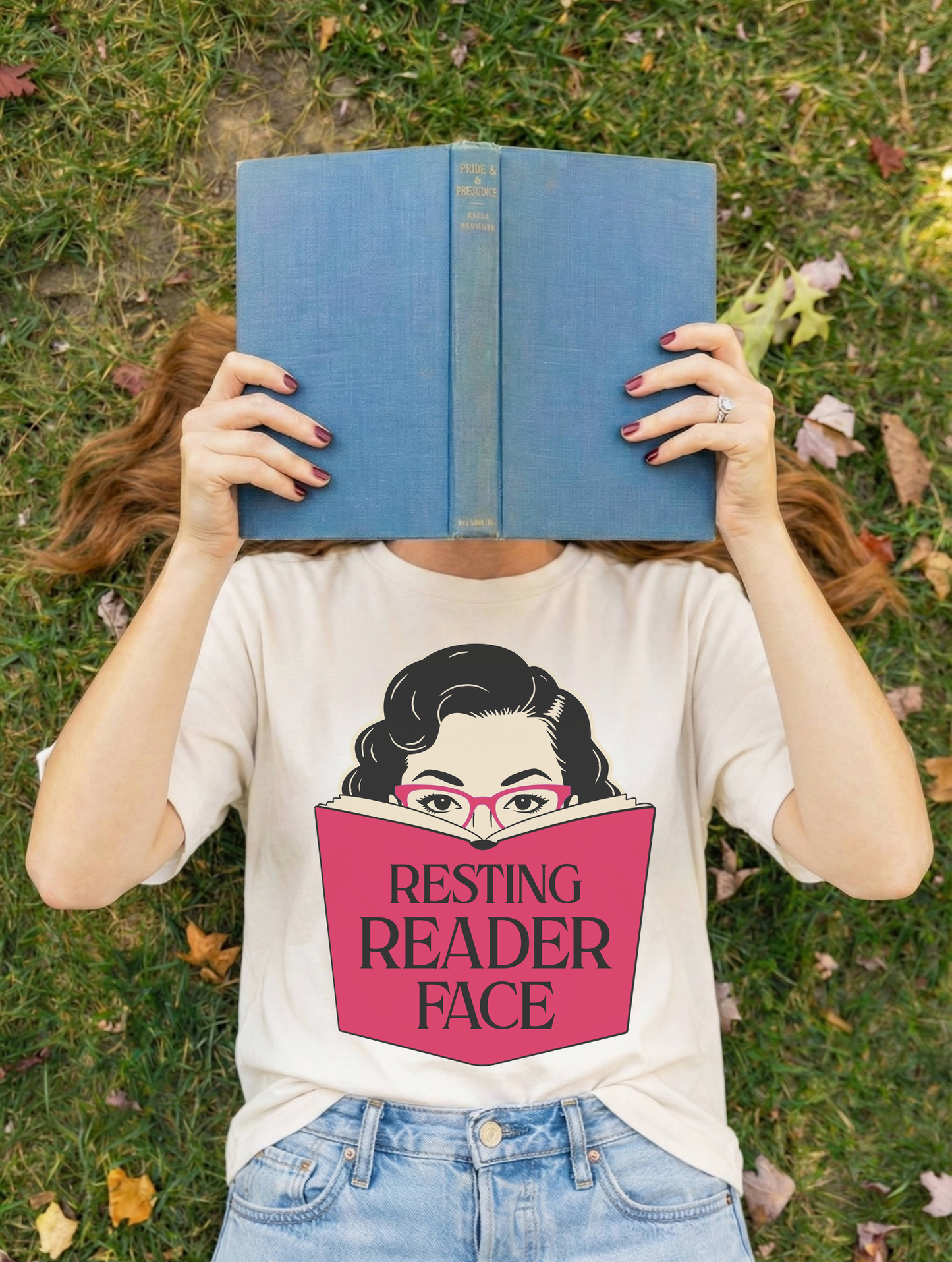 Person holding a blue book while wearing the Resting Reader Face graphic t-shirt.