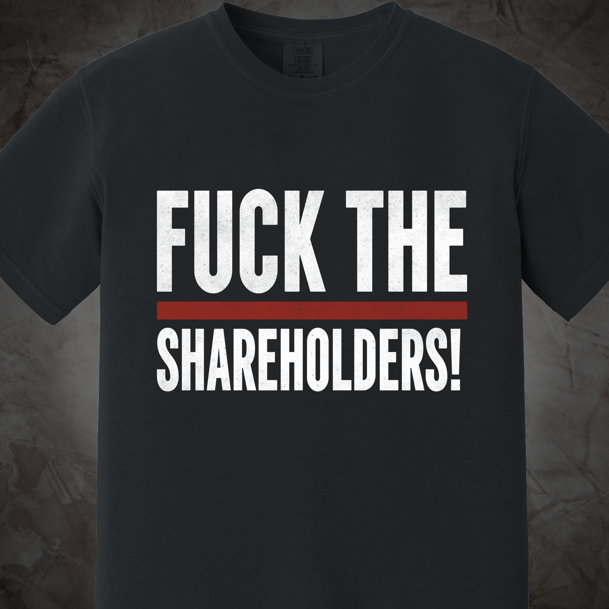 A dark charcoal gray crewneck t-shirt featuring the text 'FUCK THE SHAREHOLDERS!' printed in distressed white capital letters, separated by a single horizontal red stripe.