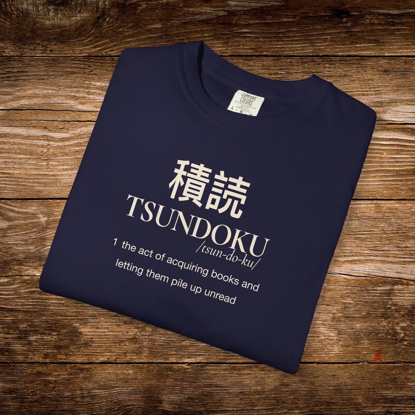 Folded navy Comfort Colors T-shirt featuring the Tsundoku dictionary definition design.