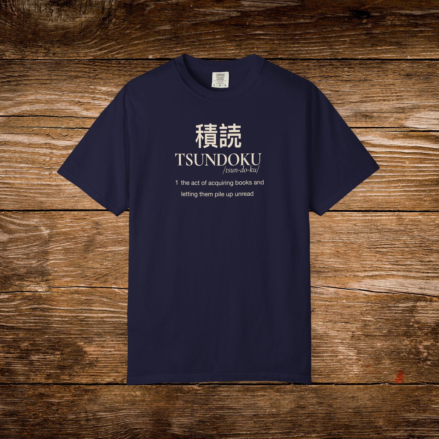 Tsundoku dictionary definition printed on a navy Comfort Colors T-shirt with minimalist vintage typography.