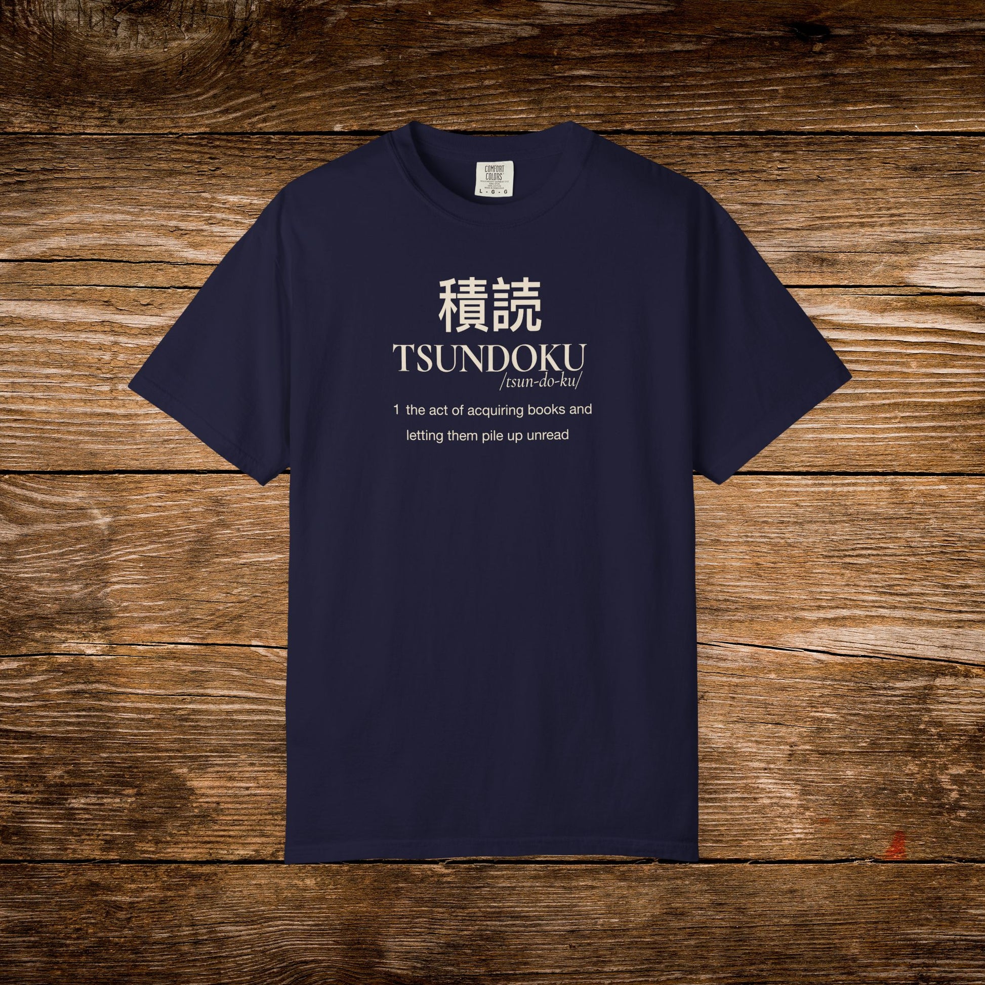 Tsundoku dictionary definition printed on a navy Comfort Colors T-shirt with minimalist vintage typography.