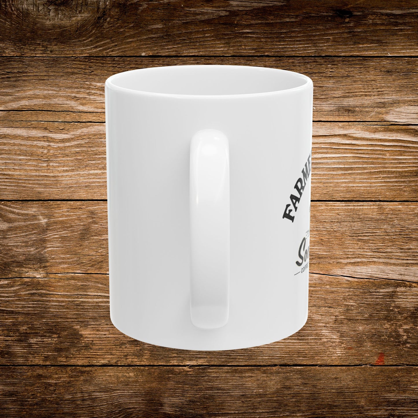 A white ceramic coffee mug with a black printed graphic, shown from a side angle against a rustic brown wooden plank background.