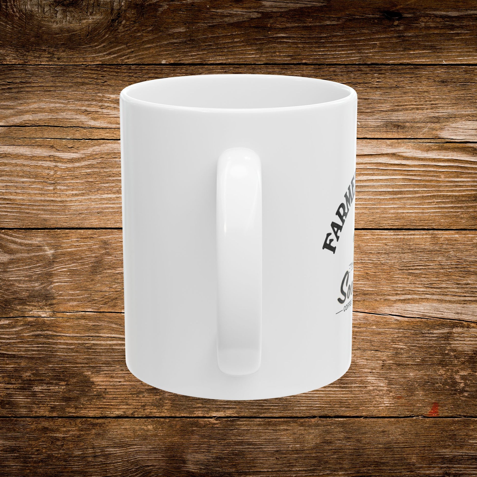 A white ceramic coffee mug with a black printed graphic, shown from a side angle against a rustic brown wooden plank background.