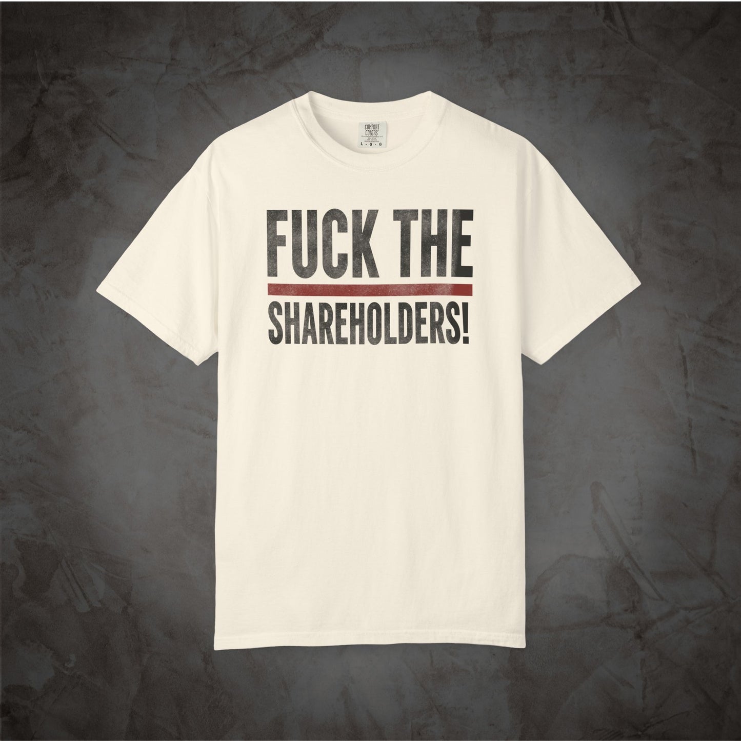 An off-white short-sleeve t-shirt with the text 'FUCK THE SHAREHOLDERS!' printed in black across the chest, separated by a thin red horizontal line, displayed against a dark textured background.
