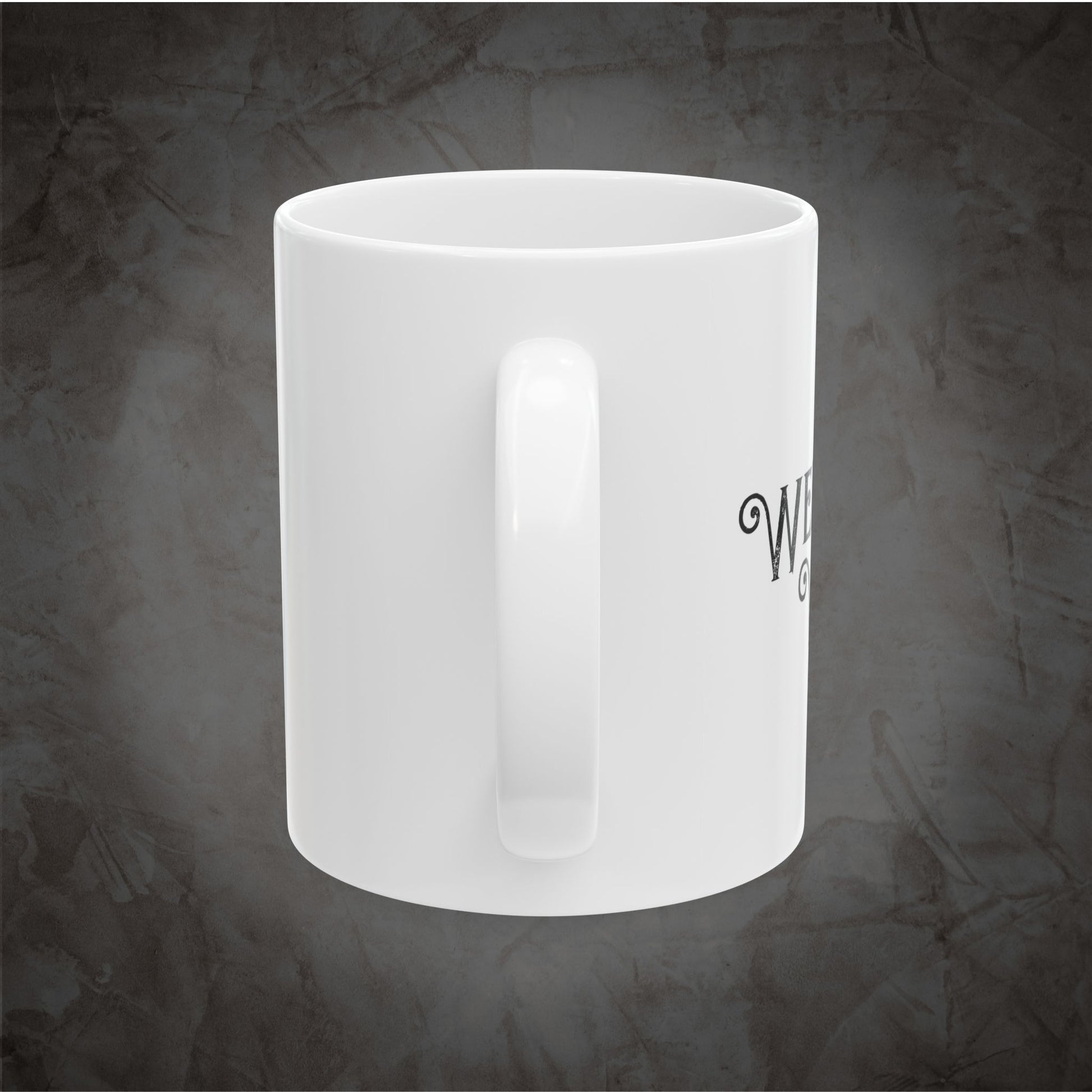 A white ceramic coffee mug with a handle, featuring partial black text on the side, set against a textured dark gray background.