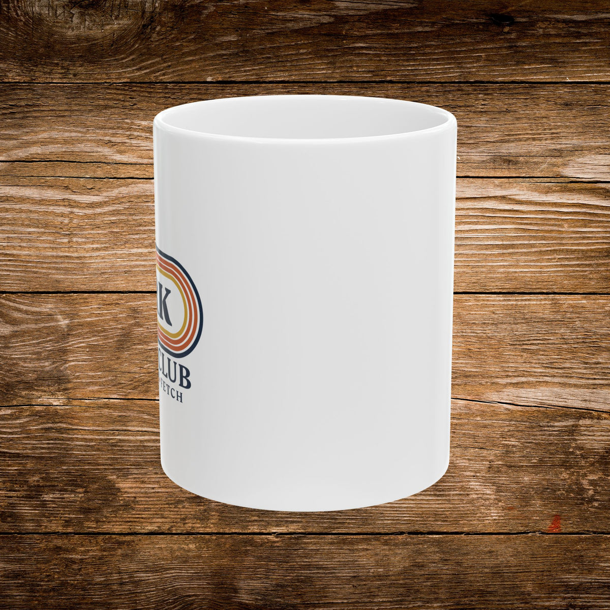 A white ceramic mug with a partial colorful logo on the side, set against a rustic brown wooden plank background.
